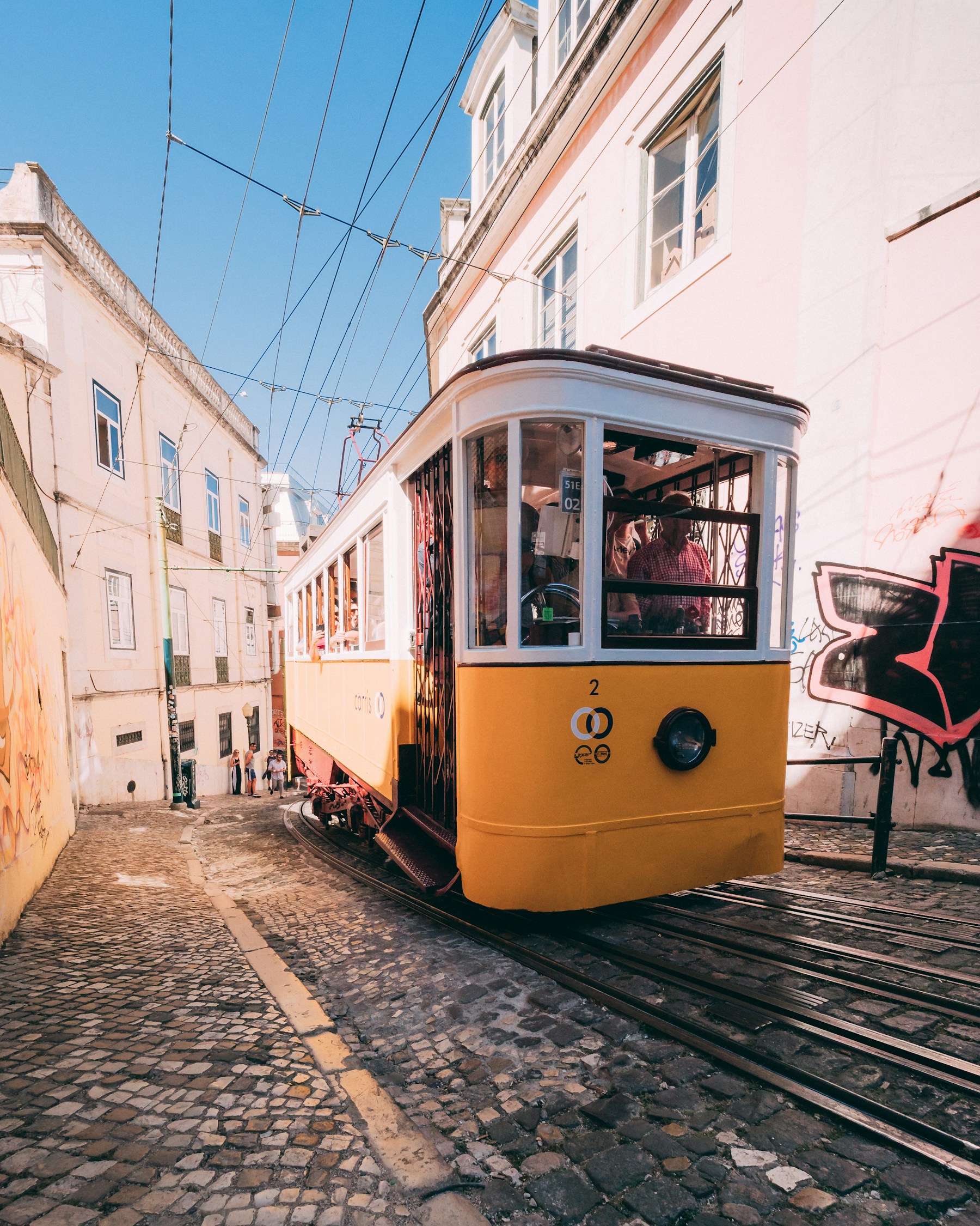 Yellow Lisbon tram climbing a narrow city street
