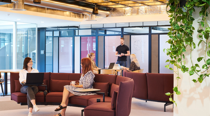 People working in a modern collaborative office lounge.